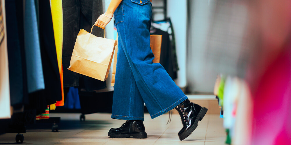 An elegant woman is shopping for clothes in a second-hand store or thrift shop.